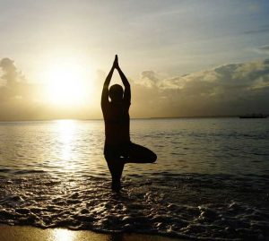 Woman balancing a yoga pose on beach